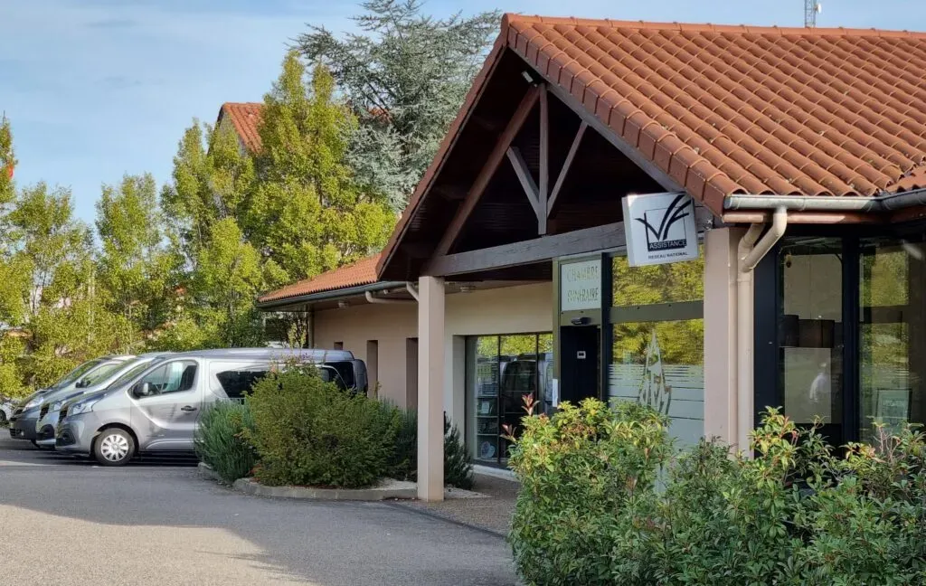 Façade de l'entreprise funéraire avec parking et véhicules de service.