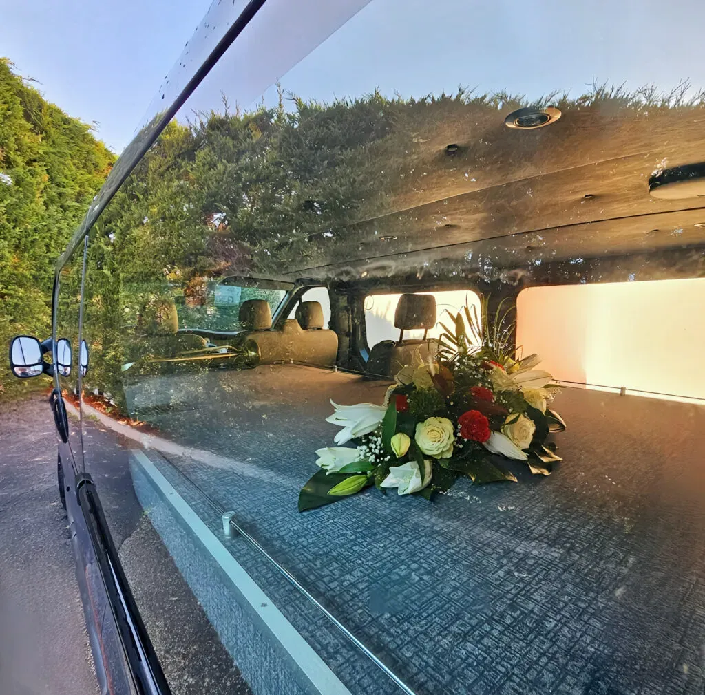 Vue de l'intérieur d'un fourgon funéraire avec une composition florale.