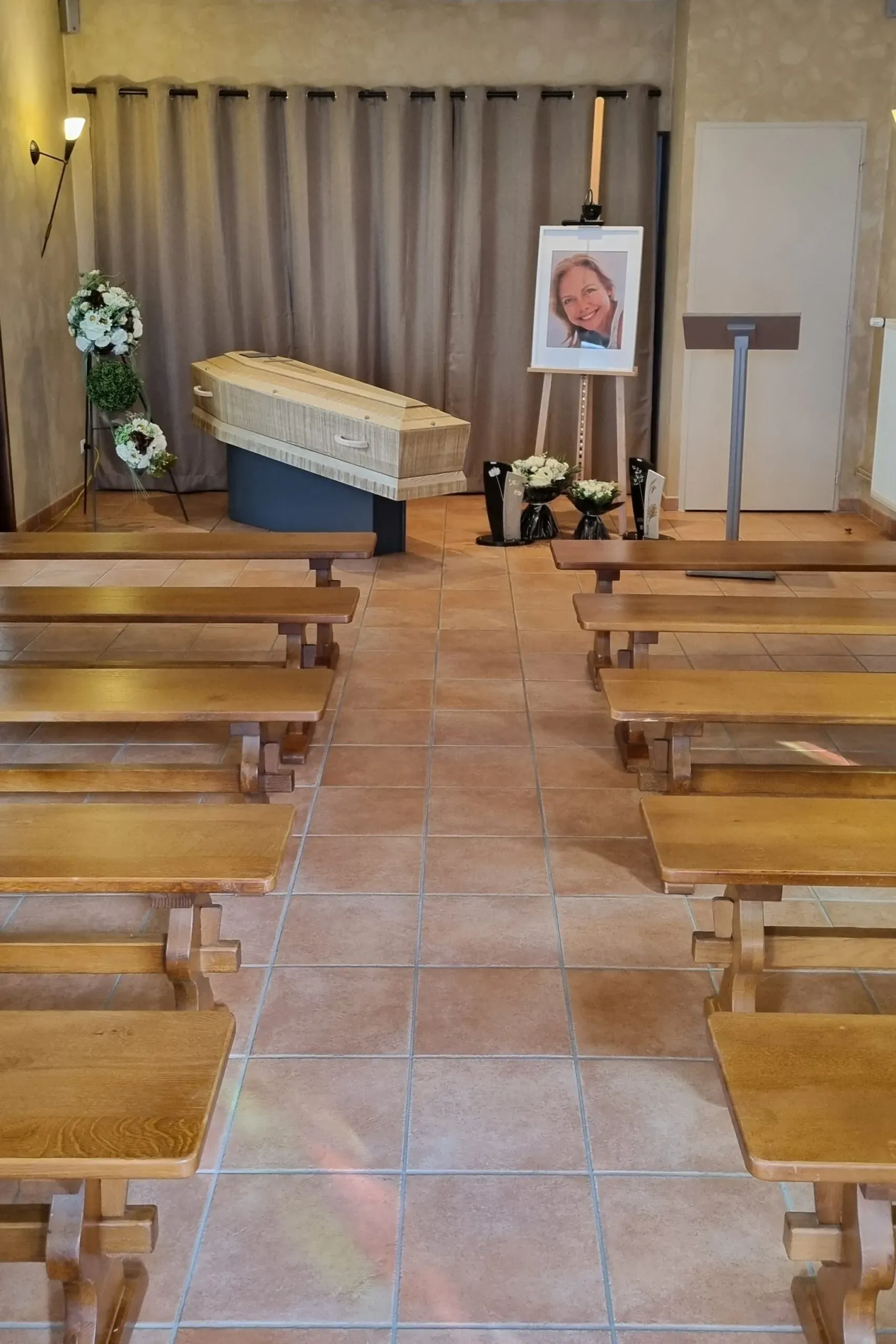 Intérieur d'un funérarium avec un cercueil en bois clair et une photo de la défunte.