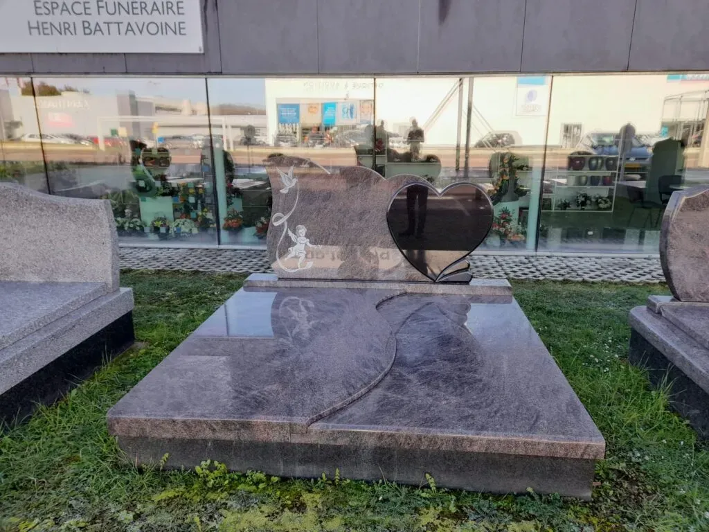 Monument funéraire en granit violet avec stèle en forme de cœur et gravure d'ange.
