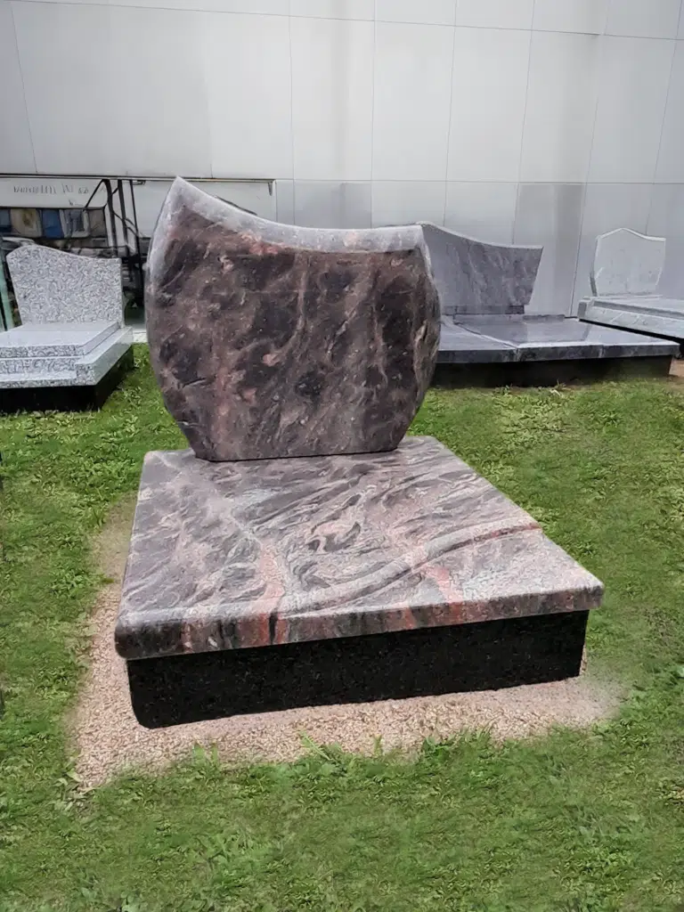 Monument funéraire en granite rose et gris poli avec motifs de vagues.