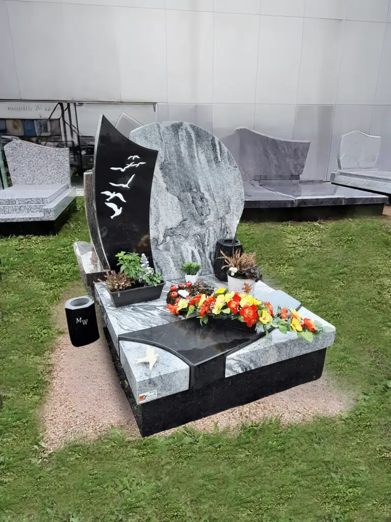 Monument funéraire en granite bicolore avec stèle sculptée d'oiseaux et fleurs.